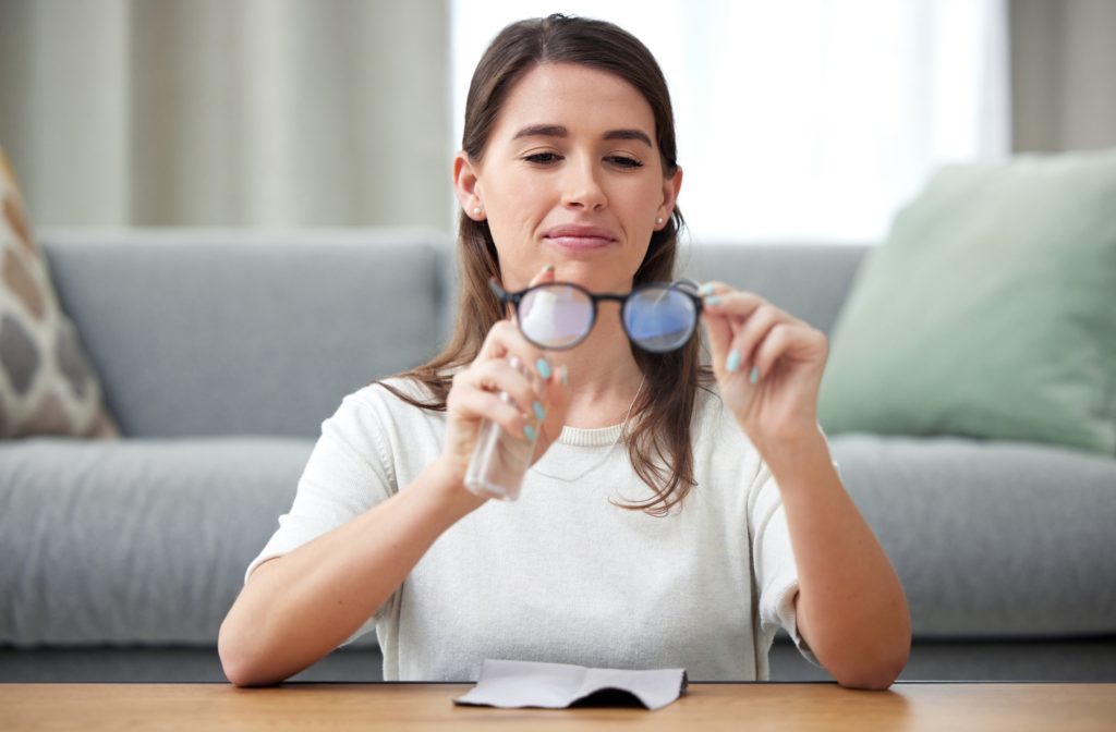 Home, cleaning and glasses with woman, lens and eye care protection with liquid, bottle and optic m